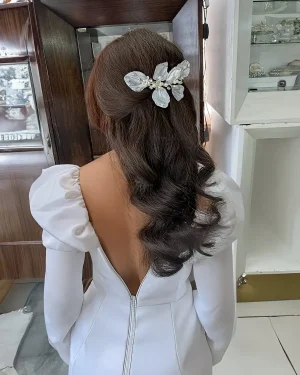 Tocado de novia en resina con hojas y perlas Linna Tocado de novia en resina con hojas y perlas diseñado para aportar un acabado delicado y con carácter al peinado. El modelo Linna combina hojitas de resina con perlas, creando un diseño que aporta textura y movimiento. Su composición realza la feminidad del look y aporta un toque de romanticismo sutil, ideal para novias que buscan destacar con elegancia sin recargar. Este tocado de novia en resina con hojas y perlas se integra con facilidad en distintos estilos: Recogidos elegantes Moños suaves Semirecogidos naturales Puede colocarse en diferentes zonas del cabello, logrando un resultado limpio y bien equilibrado. Su estructura ligera permite un uso cómodo durante toda la celebración, manteniendo firmeza y un ajuste seguro. Una opción ideal para novias que buscan un accesorio con detalles finos, un aire romántico y una estética natural. 📏 Detalles Material: Resina y perlas Diseño: Hojas Estilo: Natural / Delicado Uso: Novia Medidas: 14 cm aprox. Puede existir una pequeña variación en el tamaño.