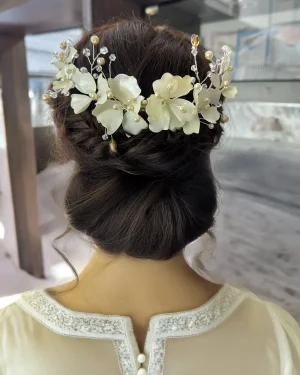 Tocado de novia flores ivory con perlas Patricia Tocado de novia flores ivory con perlas diseñado para realzar el peinado con un acabado clásico y luminoso. El modelo Patricia combina flores en resina en tonos ivory (beige o crema) con delicadas perlas, creando un conjunto armonioso que aporta profundidad y calidez al look. Su diseño destaca por su equilibrio, logrando un efecto refinado que acompaña sin sobrecargar. Este tocado de novia flores ivory con perlas es ideal para novias que buscan una estética cuidada, con detalles suaves y bien integrados. Se adapta fácilmente a distintos estilos de peinado: Recogidos elegantes Moños definidos Semirecogidos con volumen Puede colocarse en diversas zonas del cabello, logrando un acabado limpio que enmarca el peinado con naturalidad. Su estructura ligera permite llevarlo con comodidad durante toda la celebración, manteniendo firmeza y un ajuste seguro. Una opción ideal para quienes buscan un accesorio con presencia sutil y un estilo atemporal. 📏 Detalles Material: Resina y perlas Color: Ivory (beige/crema) Estilo: Clásico / Femenino / Refinado Uso: Novia Medidas: 23 cm aprox. Puede existir una pequeña variación en el tamaño.
