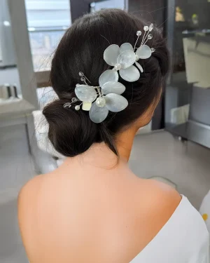 Tocado de novia en resina con flores Renata Tocado de novia en resina con flores diseñado para aportar un acabado delicado y natural al peinado. El modelo Renata incorpora tres flores de resina con detalles de perlas y cristales, logrando un diseño que aporta presencia sin recargar. Su composición permite destacar el peinado con un toque cuidado y elegante. Este tocado de novia en resina con flores es ideal para quienes buscan un accesorio sencillo pero con intención, que complemente el look sin quitar protagonismo. Se adapta fácilmente a distintos estilos: Recogidos elegantes Moños definidos Semirecogidos suaves Puede ubicarse en distintas zonas del cabello, logrando un resultado limpio y bien integrado. Su estructura ligera permite llevarlo cómodamente durante toda la celebración, manteniendo firmeza y un ajuste seguro. Una opción ideal para novias que buscan un diseño sobrio, con detalles delicados y fácil de combinar. 📏 Detalles Material: Resina, perlas y cristales Estilo: Delicado / Equilibrado / Natural Uso: Novia Medidas: 13 cm aprox. Puede existir una pequeña variación en el tamaño.